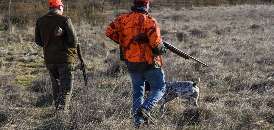 Zwei Jäger mit Hund auf Lichtung